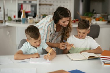 Anne oğullarıyla ödev yapıyor.