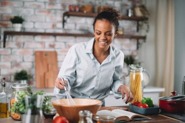 Güzel bir kadın yemek pişiriyor ve mutfakta eğleniyor. Kız mutfakta sağlıklı yemek pişiriyor..