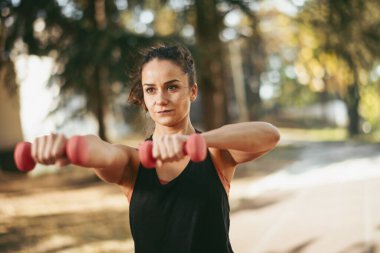 Genç bir kadın dışarıda egzersiz yapıyor. 