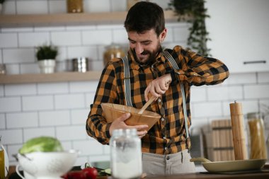Mutfaktaki yakışıklı adamın portresi. Genç adam lezzetli yemekler hazırlıyor..