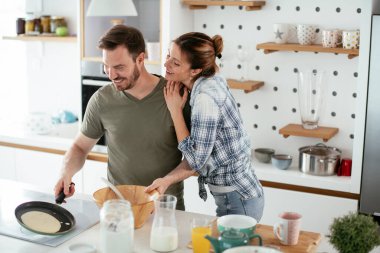 Çift evde birlikte yemek pişiriyor ve yemek hazırlıyor.