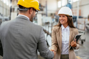 Mutlu iş adamı ve iş kadını el sıkışması fabrikada