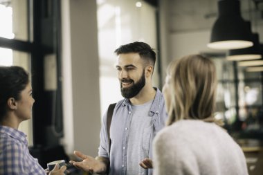 Modern açık uzay ofisinde sıradan iş adamlarından oluşan bir grup. İş kadınları ve işadamları yeni proje hakkında konuşuyor.