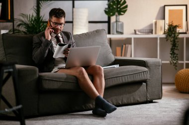 Evde pantolonsuz çalışan bir iş adamı. Genç adam video görüşmesi sırasında bilgisayarı kullanıyor..