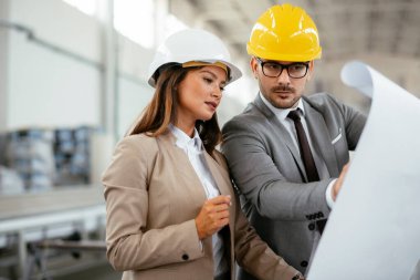 İşadamı ve işkadını fabrikadaki yeni iş projesini tartışıyor