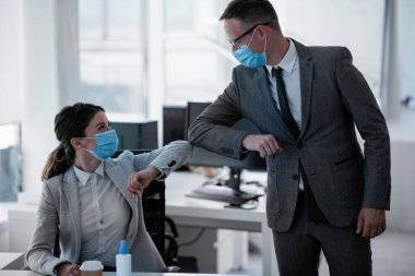 Ofiste tıbbi maskeli bir iş adamı ve iş kadını var. Covid-19 saatinde selamlar..