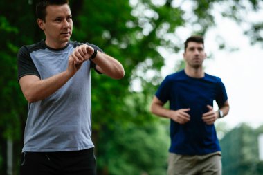 Gençler yarış pistinde antrenman yapıyor. İki genç arkadaş atletizm pistinde koşuyor.