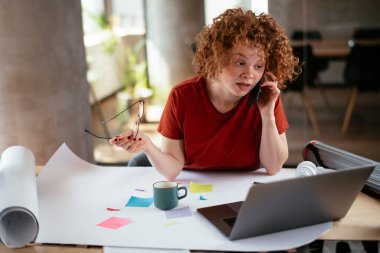 Projeler üzerinde çalışan güzel bir iş kadını. Genç iş kadını telefonda konuşuyor..