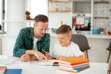 Baba, oğluna ev ödevinde yardım ediyor. Küçük çocuk evde öğreniyor..