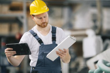 Üretim hattındaki fabrika işçisi. Fabrikada çalışan sarı kasklı adam..