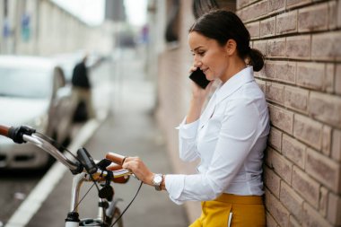 Akıllı telefon kullanan bisikletli genç bir kadın.