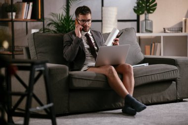 Evde pantolonsuz çalışan bir iş adamı. Genç adam video görüşmesi sırasında bilgisayarı kullanıyor..