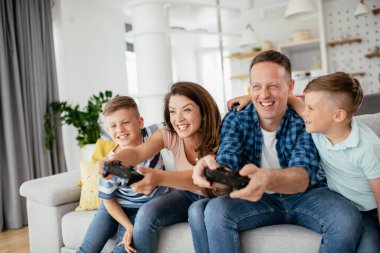 Anne ve baba evde çocuklarla video oyunu oynarken eğleniyorlar..