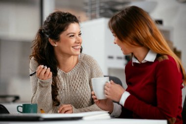 Açık uzay ofisinde konuşan ve gülen mutlu iş kadınları