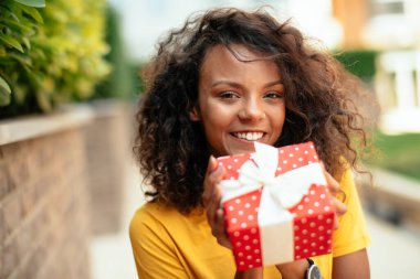 Genç Afrikalı bir kadın hediye veriyor.