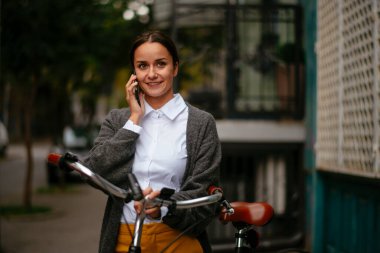 Akıllı telefon kullanan bisikletli genç bir kadın.