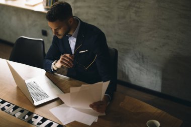 Ofiste dizüstü bilgisayarla çalışan bir iş adamı. Toplantı odasında iş süitinde bir adam var. Kağıt raporlarıyla şirket yöneticiliği.