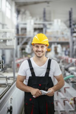 Fabrika işçisi. Genç adam fabrika ortamında çalışıyor.