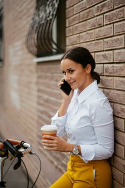 Akıllı telefon kullanan bisikletli genç bir kadın.