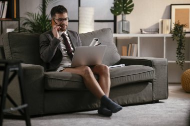 Evde pantolonsuz çalışan bir iş adamı. Genç adam video görüşmesi sırasında bilgisayarı kullanıyor..