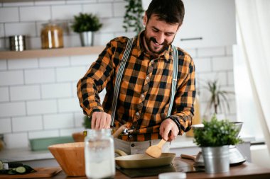 Mutfaktaki yakışıklı adamın portresi. Genç adam lezzetli yemekler hazırlıyor..