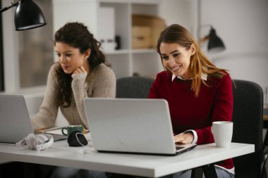 Açık uzay ofisinde konuşan ve gülen mutlu iş kadınları