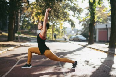 Genç bir kadın dışarıda egzersiz yapıyor. 