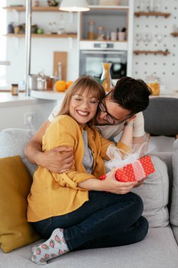 Erkek arkadaşı kız arkadaşına hediyeyle sürpriz yapıyor. Genç adam karısına hediye kutusu veriyor.