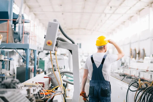 Üretim hattındaki fabrika işçisi. Fabrikada çalışan sarı kasklı adam..