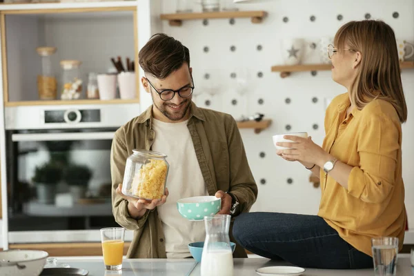 Genç çift evde kahvaltı hazırlıyor. Sevgi dolu çift mutfakta mısır gevreği yiyor..