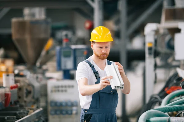 Üretim hattındaki fabrika işçisi. Fabrikada çalışan sarı kasklı adam..