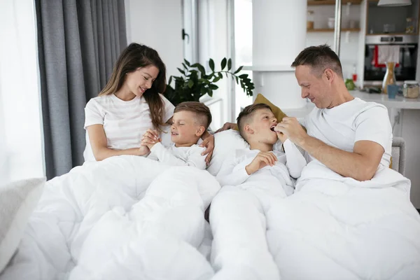 Молодая Семья Наслаждается Постели Счастливые Родители Сыновьями Отдыхающими Постели — стоковое фото