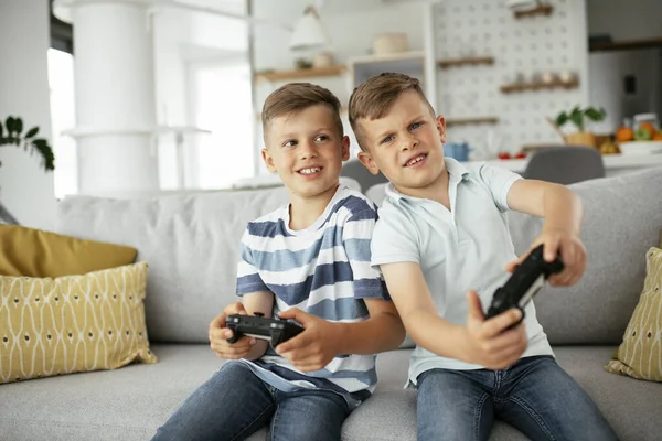 Video oyunu oynayan mutlu kardeşler. Küçük kardeşler oturma odasında video oyunu oynarken eğleniyorlar.