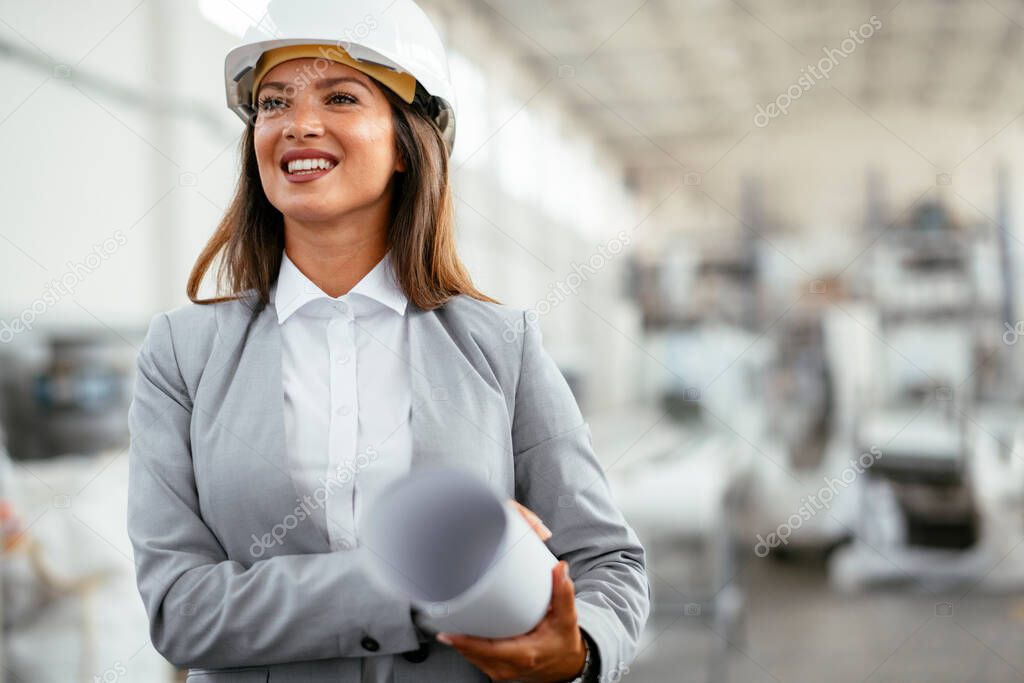 portrait of beautiful architect woman with blueprint standing in a factory