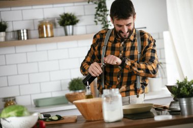 Mutfaktaki yakışıklı adamın portresi. Genç adam lezzetli yemekler hazırlıyor..