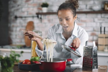 Güzel bir kadın yemek pişiriyor ve mutfakta eğleniyor. Kız mutfakta sağlıklı yemek pişiriyor..