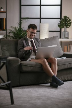 Evde pantolonsuz çalışan bir iş adamı. Genç adam video görüşmesi sırasında bilgisayarı kullanıyor..