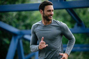 Genç adam şehirde koşuyor. Dışarıda antrenman yapan mutlu bir sporcu.