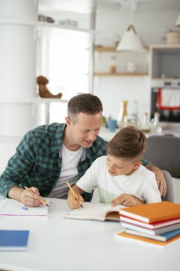 Baba, oğluna ev ödevinde yardım ediyor. Küçük çocuk evde öğreniyor..
