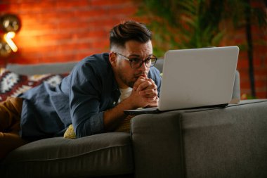 Evdeki dizüstü bilgisayarda dizi izleyen bir adam..