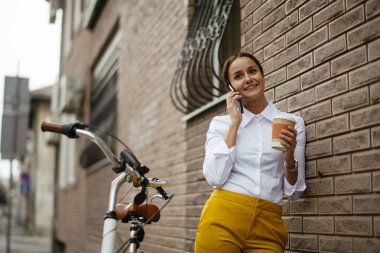 Akıllı telefon kullanan bisikletli genç bir kadın.