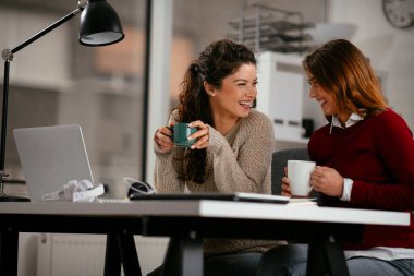 Açık uzay ofisinde konuşan ve gülen mutlu iş kadınları