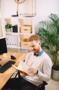 Genç yakışıklı işadamı ofiste notlar okuyor.