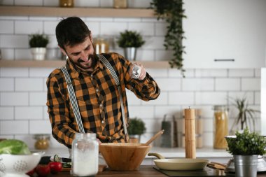 Mutfaktaki yakışıklı adamın portresi. Genç adam lezzetli yemekler hazırlıyor..