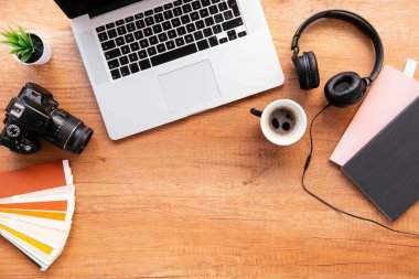 Ofis masasının en üst görüntüsü. Dizüstü bilgisayarlı ahşap masa, bir fincan kahve ve malzeme..