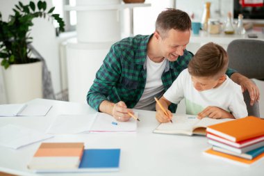 Baba, oğluna ev ödevinde yardım ediyor. Küçük çocuk evde öğreniyor..