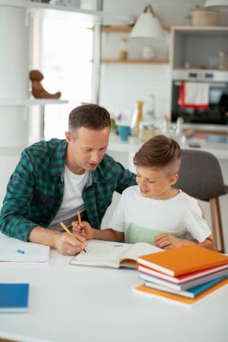 Baba, oğluna ev ödevinde yardım ediyor. Küçük çocuk evde öğreniyor..