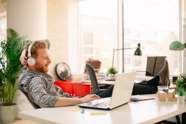 Ofisteki iş adamı. Kulaklıkla müzik dinleyen yakışıklı kızıl adam.