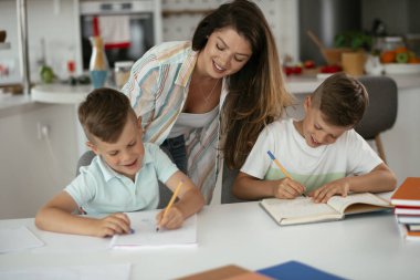 Anne oğullarıyla ödev yapıyor.