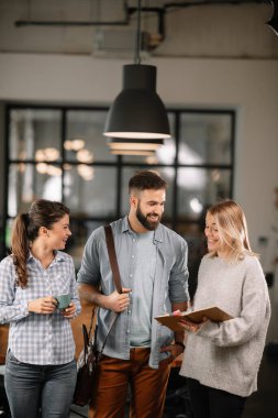 Modern açık uzay ofisinde sıradan iş adamlarından oluşan bir grup. İş kadınları ve işadamları yeni proje hakkında konuşuyor.